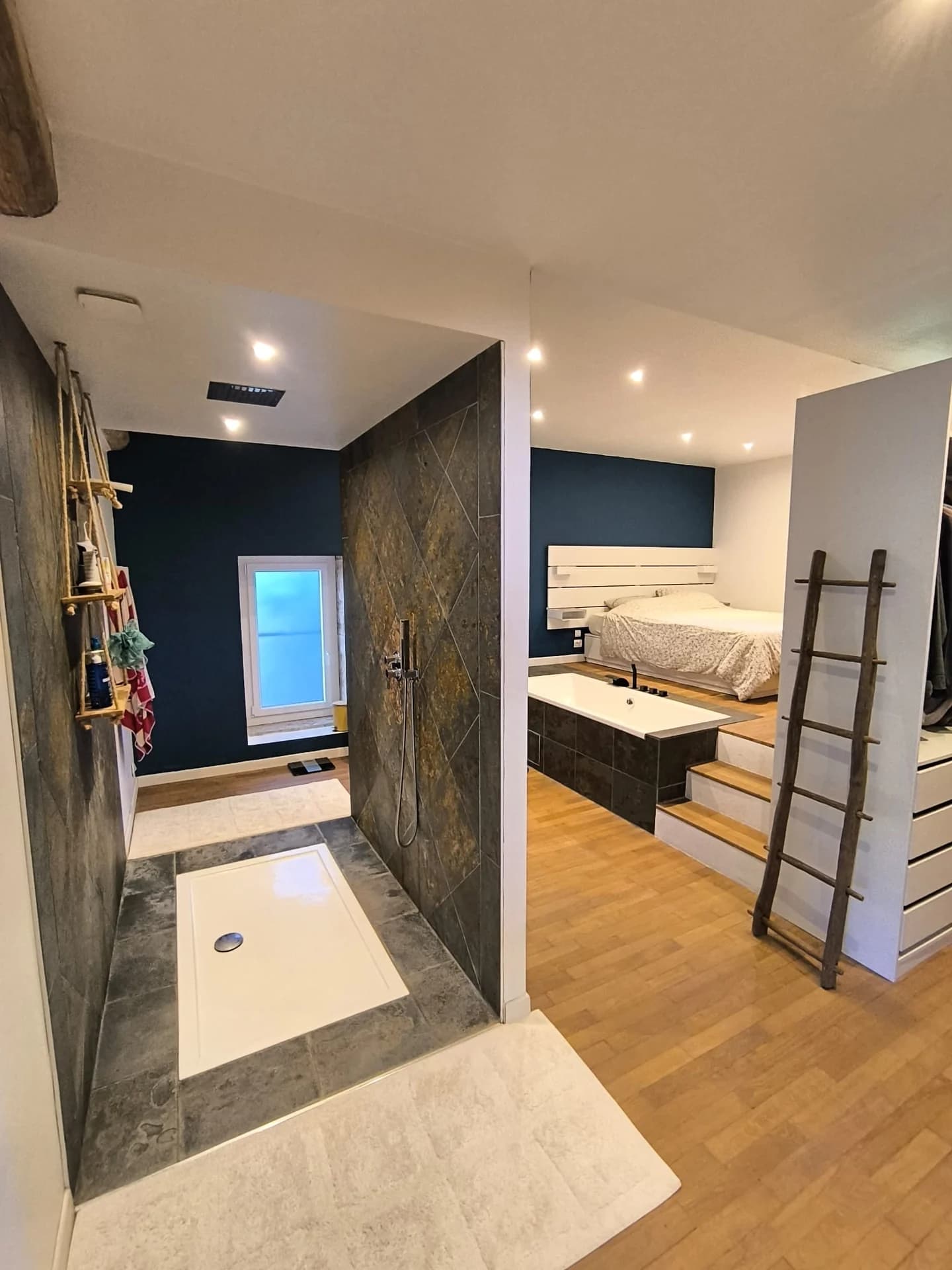 Suite parentale avec chambre, baignoire et douche séparée par une cloison carrelée