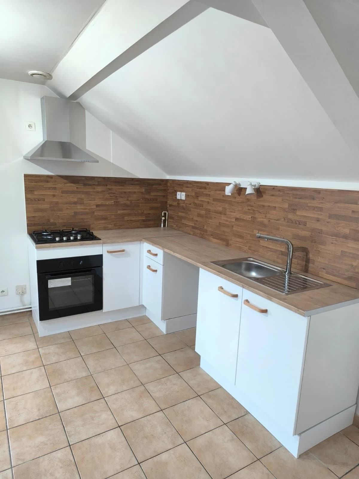Cuisine blanche sous pente avec crédence effet bois, aménagement en cours
